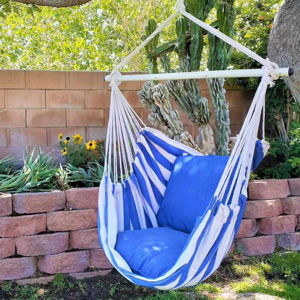 A blue and white hammock chair hanging in a sunny garden